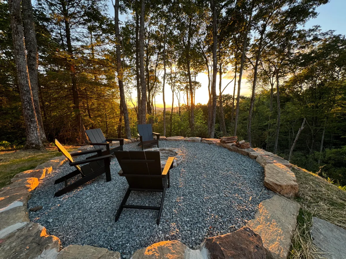 A cozy fire pit circle with Adirondack chairs surrounded by forest, set up for intimate gatherings. The natural setting invites guests to relax, share stories, and enjoy evenings under the stars.