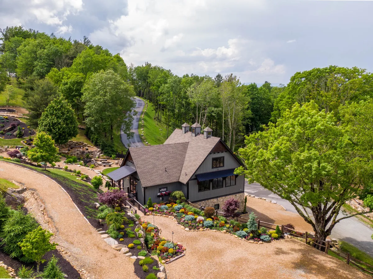 The image presents the exterior of a house with a landscaped garden and a winding driveway, all bathed in soft sunset light. The scene is peaceful and welcoming, hinting at the close proximity and ease of access to nearby attractions like the Eagles Nest Winery.